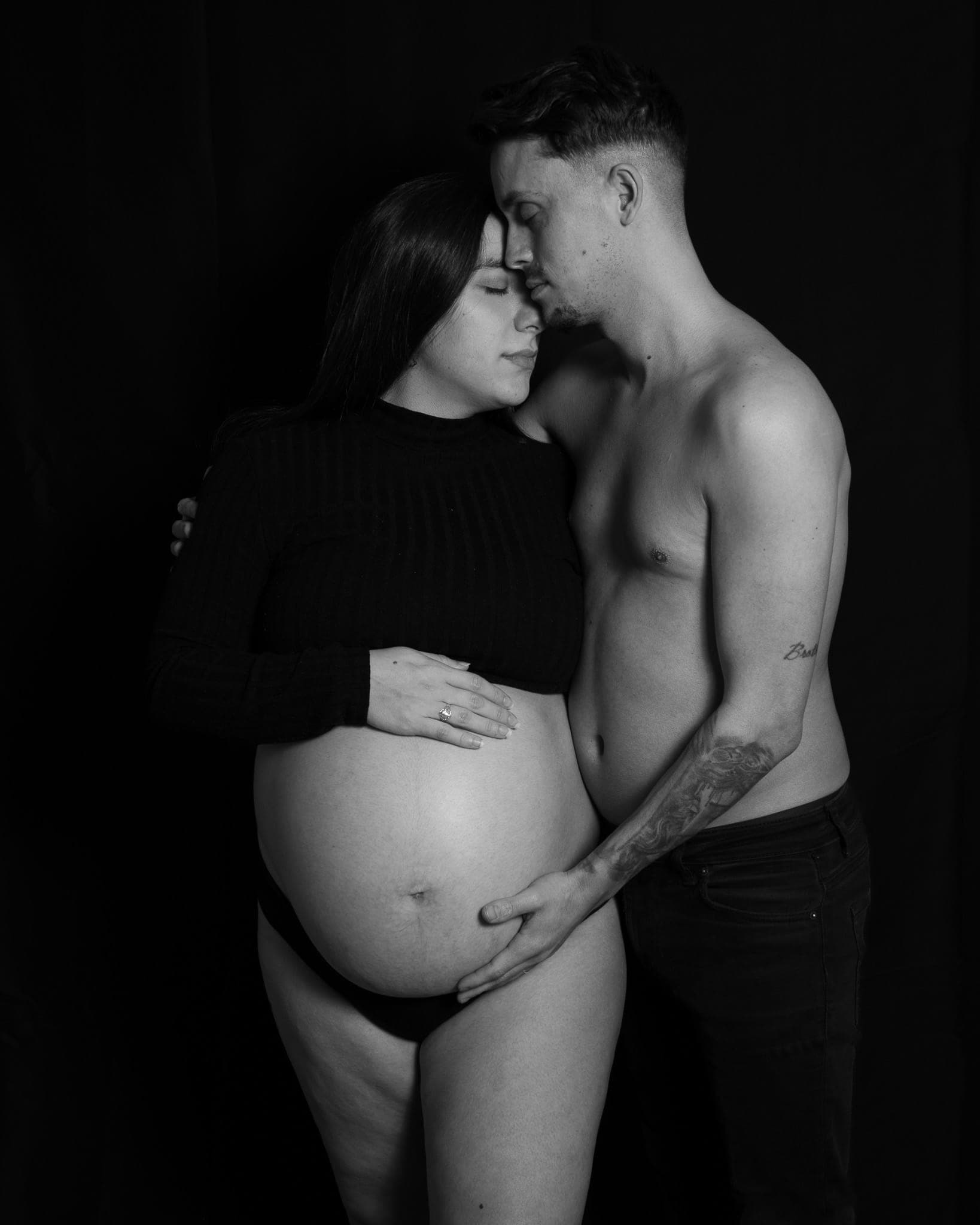 Fotografía artística de embarazo en Sevilla — barriga con luz lateral sobre fondo oscuro