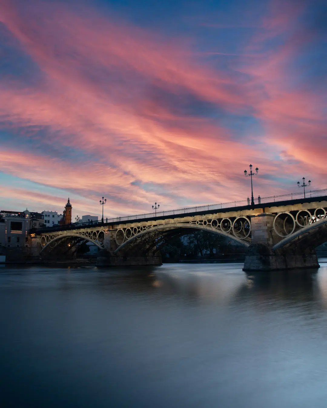 Atardecer en el puente de Triana en Sevilla, reflejado en el río Guadalquivir