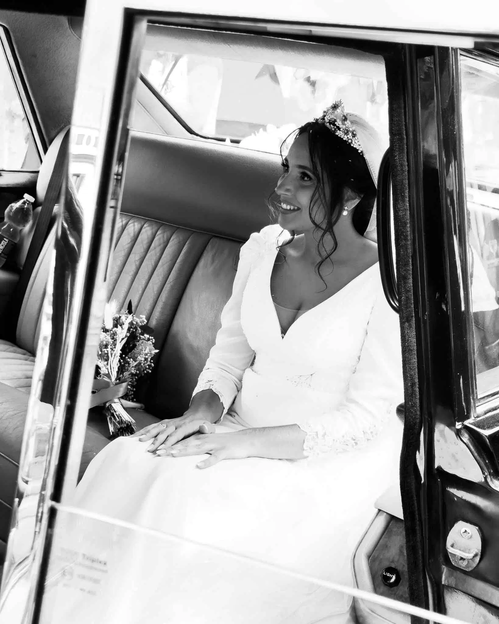 Novia sonriente dentro de un coche clásico en Sevilla durante un reportaje de bodas